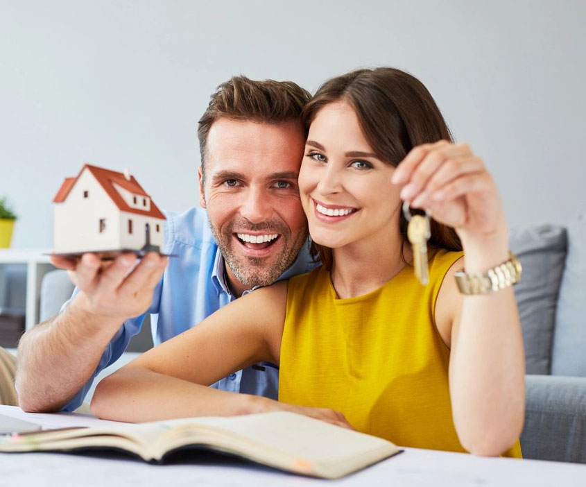 A Couple Holding a Model With a Keys