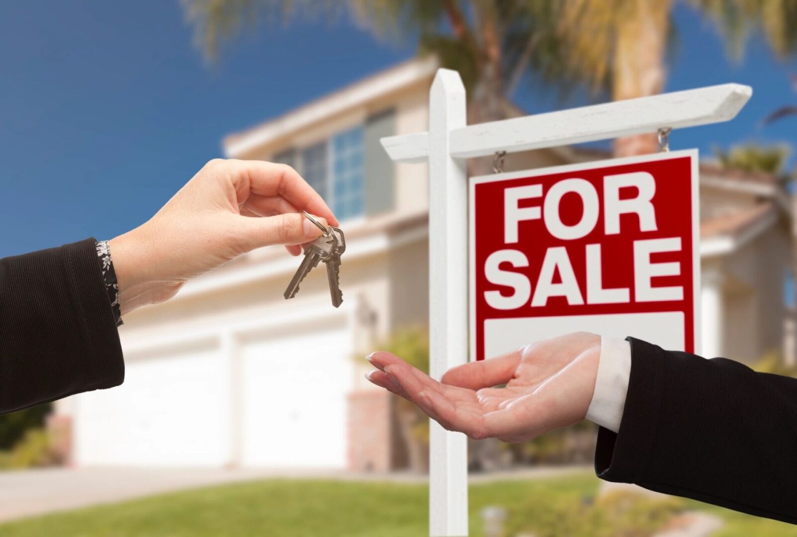 A Person Handing Keys in Front of a For Sale Board